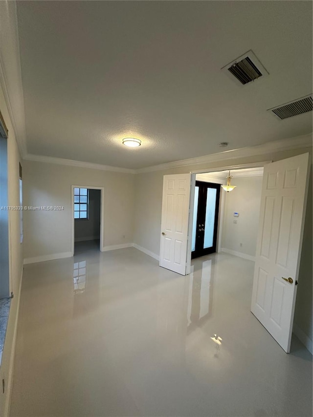 empty room with ornamental molding and a textured ceiling