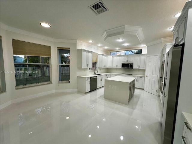 kitchen with appliances with stainless steel finishes, a kitchen island, ornamental molding, and sink