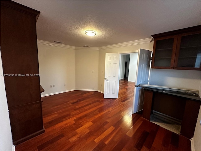 interior space featuring a textured ceiling, dark hardwood / wood-style flooring, and crown molding