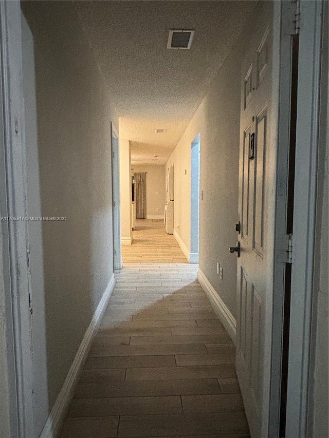 hallway featuring a textured ceiling and light hardwood / wood-style floors