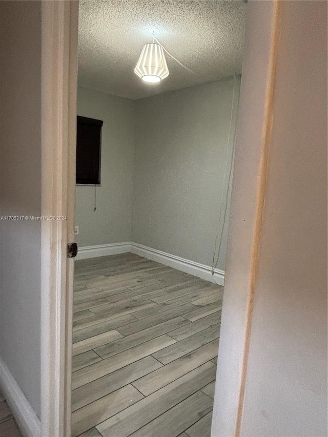 hallway with a textured ceiling and light hardwood / wood-style floors