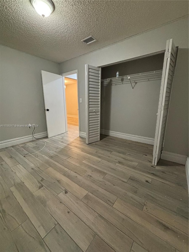 empty room featuring wood-type flooring and a textured ceiling