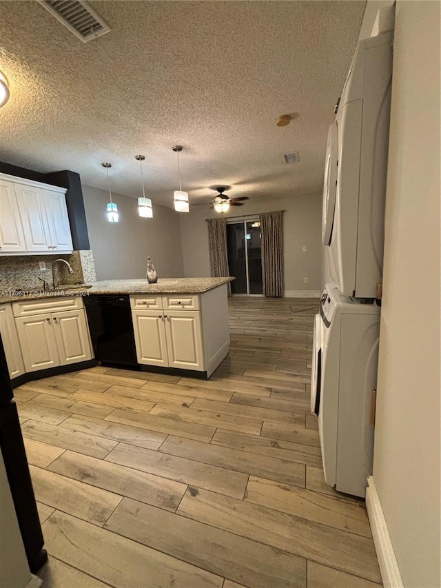 kitchen featuring dishwasher, stacked washer and clothes dryer, hanging light fixtures, light hardwood / wood-style floors, and white cabinetry