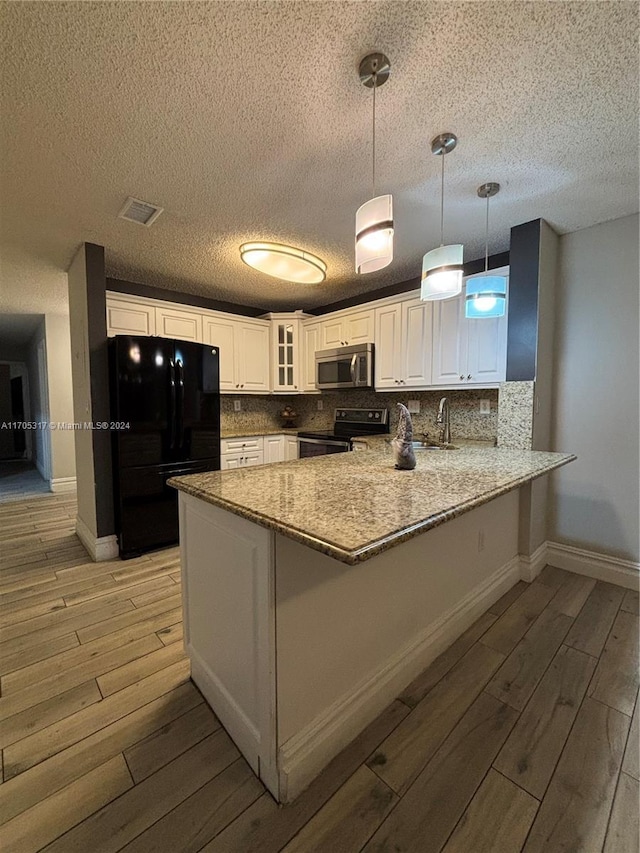 kitchen with range with electric cooktop, hanging light fixtures, black fridge, light hardwood / wood-style flooring, and kitchen peninsula