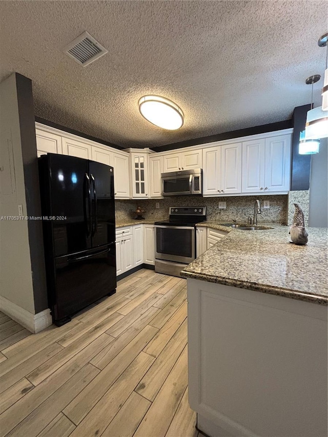 kitchen featuring sink, light hardwood / wood-style flooring, kitchen peninsula, decorative light fixtures, and appliances with stainless steel finishes