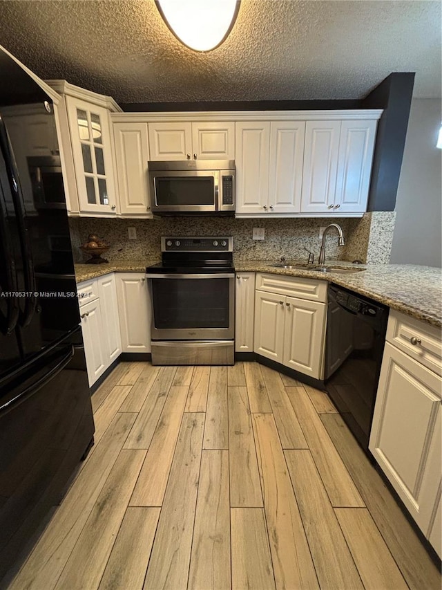 kitchen with light stone counters, a textured ceiling, black appliances, light hardwood / wood-style flooring, and white cabinets