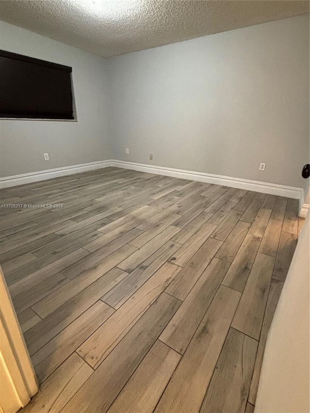 spare room with wood-type flooring and a textured ceiling