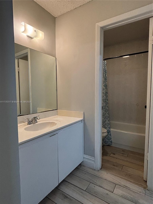 bathroom featuring vanity, wood-type flooring, a textured ceiling, and shower / tub combo with curtain