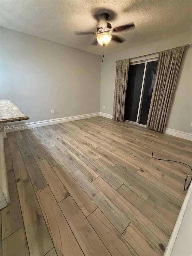 empty room with hardwood / wood-style flooring, ceiling fan, and a textured ceiling