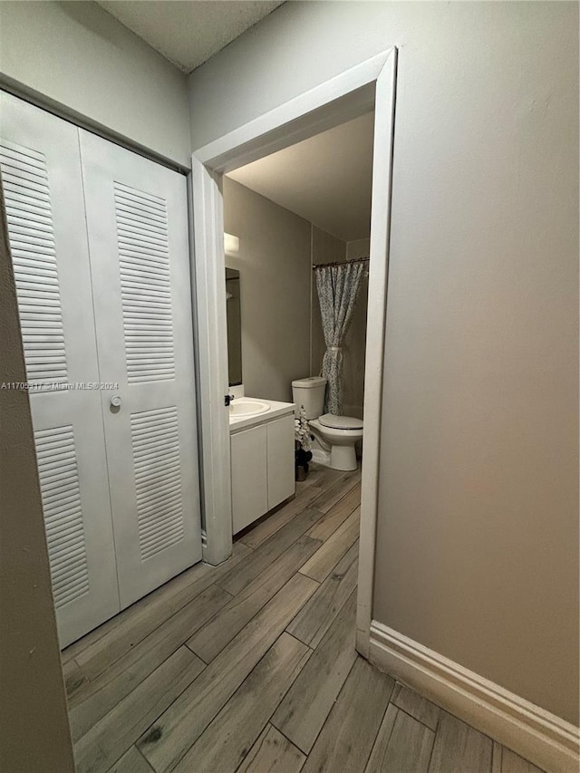 bathroom with a shower with curtain, hardwood / wood-style floors, vanity, and toilet