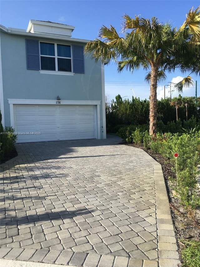 exterior space featuring decorative driveway, an attached garage, and stucco siding