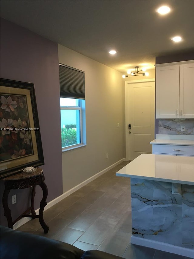 kitchen with tasteful backsplash, baseboards, light countertops, white cabinetry, and recessed lighting