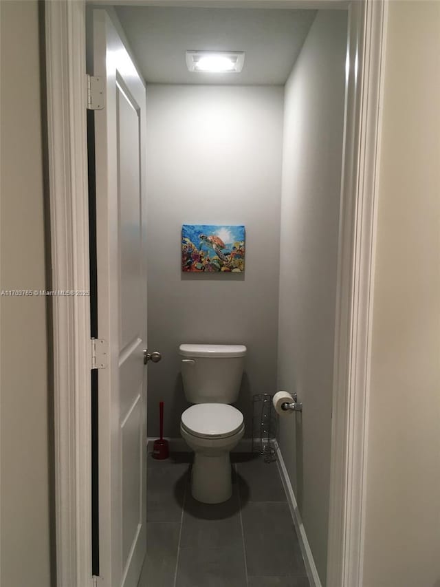 bathroom with toilet, baseboards, and tile patterned floors