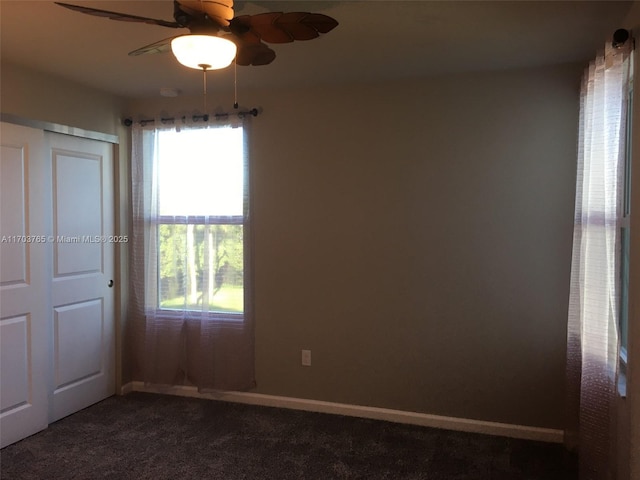 unfurnished room with ceiling fan, dark carpet, and baseboards