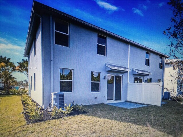 back of house with central AC, a lawn, and stucco siding