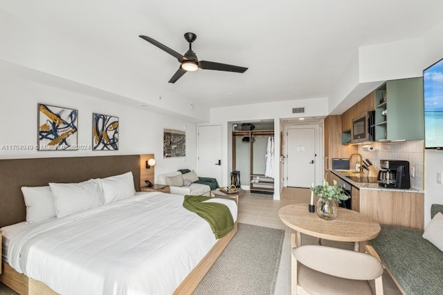 tiled bedroom featuring ceiling fan, a closet, and sink