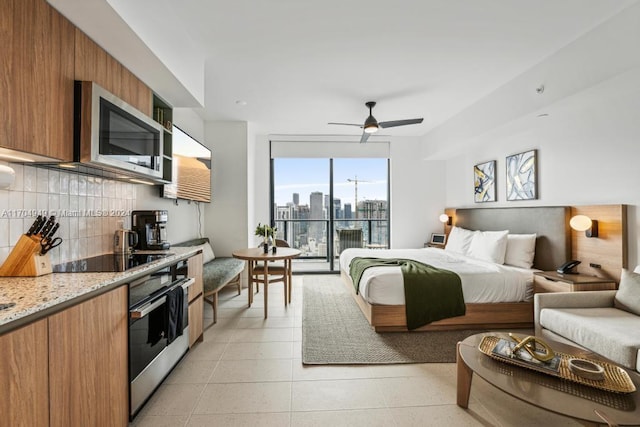 tiled bedroom with ceiling fan, expansive windows, and access to exterior