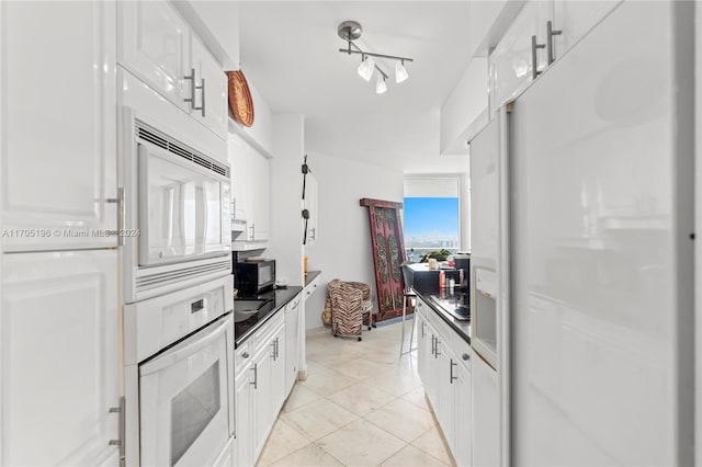 kitchen featuring white cabinets, a healthy amount of sunlight, white appliances, and light tile patterned floors