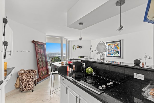 kitchen with dark stone countertops, light tile patterned floors, decorative light fixtures, white cabinetry, and gas cooktop