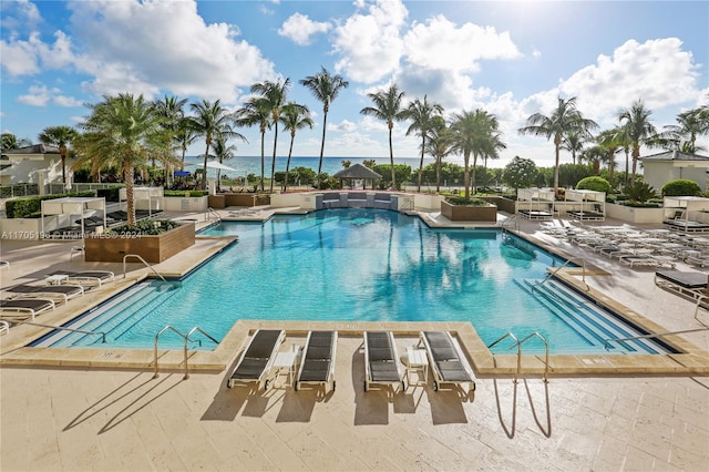 view of swimming pool with a patio area and a water view