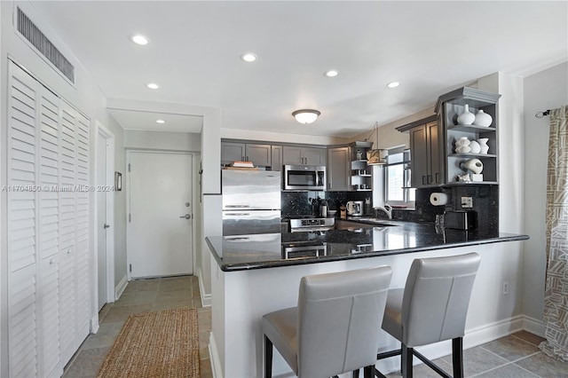 kitchen featuring sink, decorative backsplash, appliances with stainless steel finishes, decorative light fixtures, and kitchen peninsula