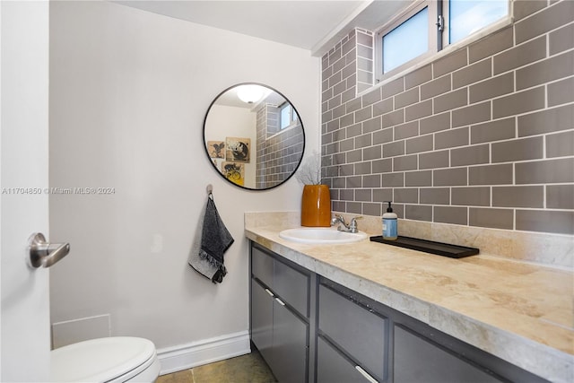 bathroom featuring tile patterned flooring, vanity, toilet, and backsplash