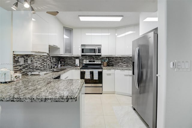 kitchen with sink, white cabinets, light tile patterned floors, kitchen peninsula, and stainless steel appliances