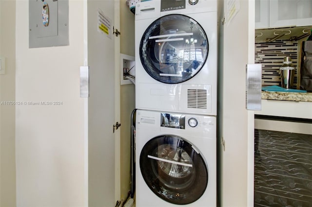 laundry area featuring stacked washer / drying machine and electric panel