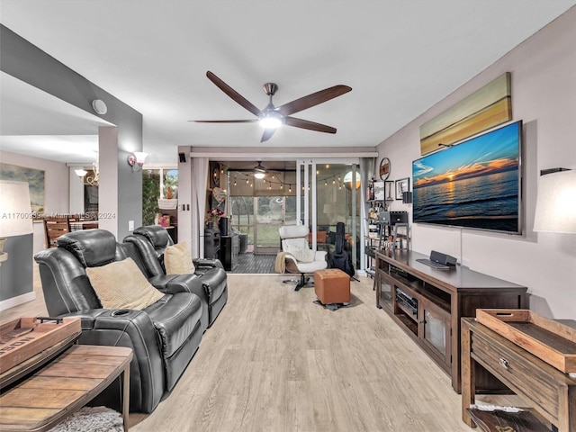 living room with ceiling fan with notable chandelier and light wood-type flooring