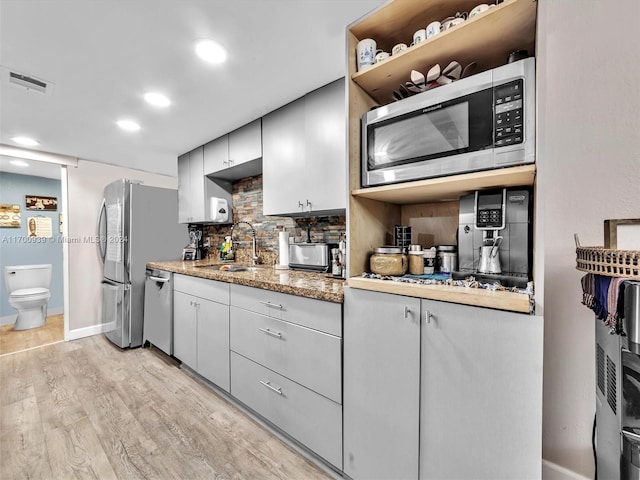 kitchen with tasteful backsplash, sink, stainless steel appliances, and light hardwood / wood-style floors