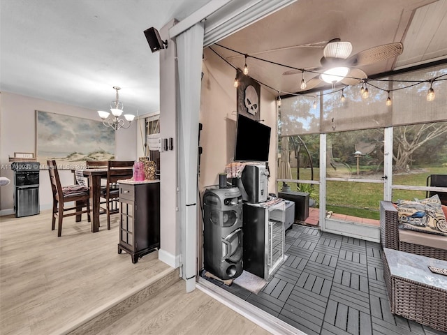 sunroom / solarium featuring ceiling fan with notable chandelier