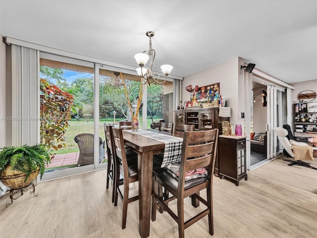 dining area featuring expansive windows, light wood-type flooring, and an inviting chandelier