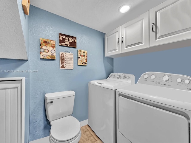 laundry area with a textured ceiling, light hardwood / wood-style flooring, and washing machine and clothes dryer