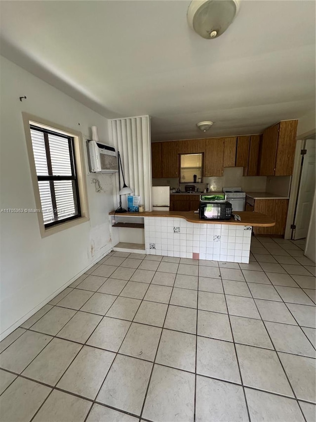 kitchen with a breakfast bar, white refrigerator, light tile patterned floors, a wall mounted AC, and kitchen peninsula