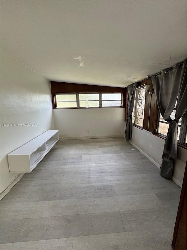 unfurnished room with plenty of natural light and vaulted ceiling