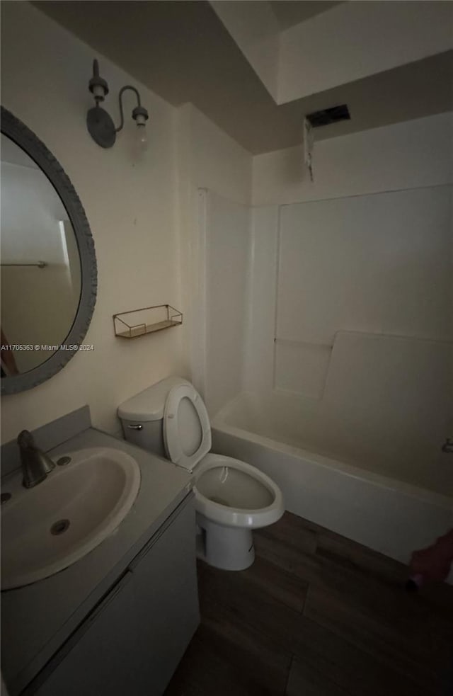 full bathroom with bathing tub / shower combination, vanity, wood-type flooring, and toilet