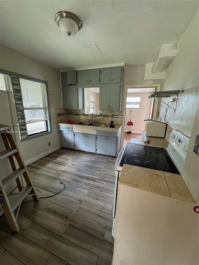 kitchen featuring white electric range oven, light wood-type flooring, and sink