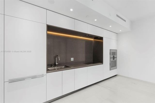 kitchen featuring black electric stovetop, a sink, white cabinets, dark countertops, and modern cabinets