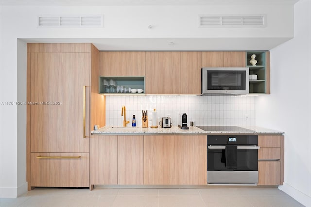 kitchen featuring appliances with stainless steel finishes, backsplash, light stone counters, and light brown cabinetry