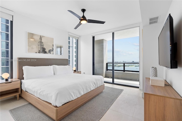 tiled bedroom with a wall of windows and ceiling fan