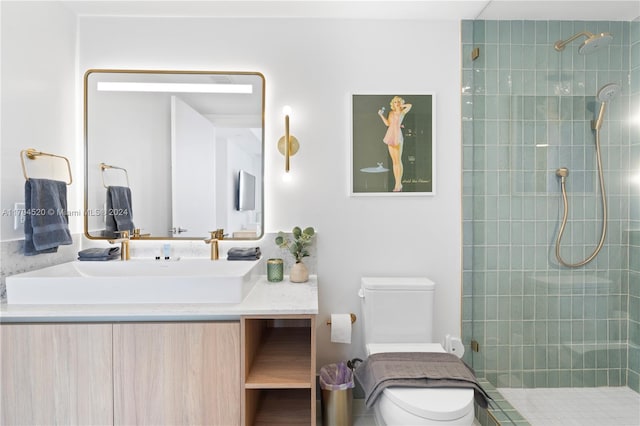 bathroom featuring a tile shower, vanity, and toilet