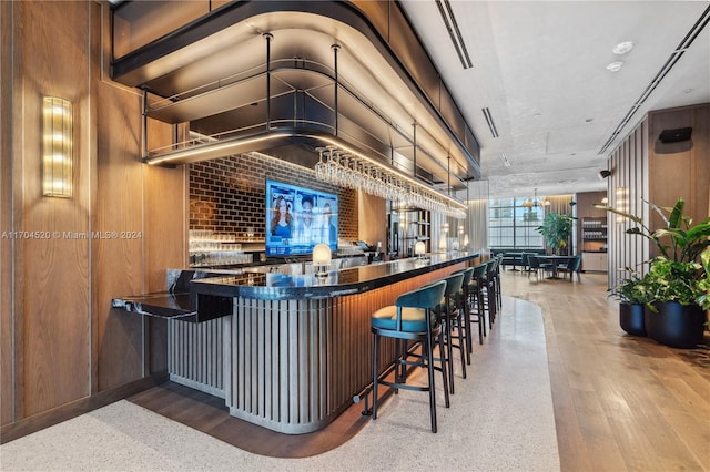 bar with vaulted ceiling, wood walls, wood-type flooring, and decorative light fixtures