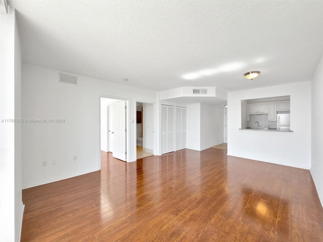 empty room featuring dark hardwood / wood-style flooring, a textured ceiling, and sink