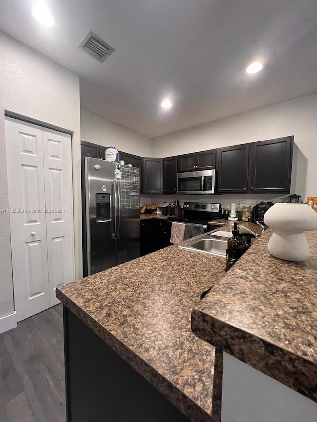 kitchen with kitchen peninsula, sink, dark hardwood / wood-style flooring, and appliances with stainless steel finishes