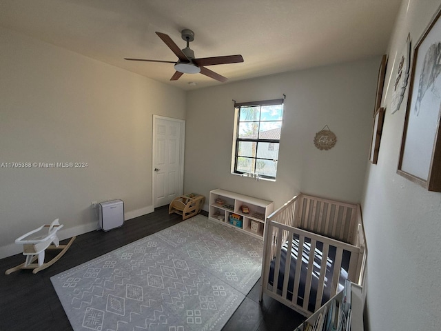 bedroom featuring ceiling fan, dark hardwood / wood-style floors, and a crib