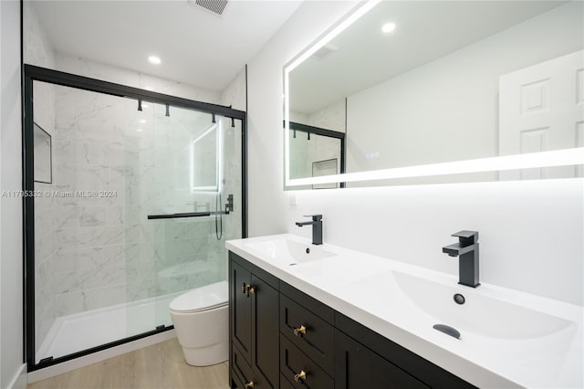 bathroom with hardwood / wood-style floors, vanity, a shower with door, and toilet