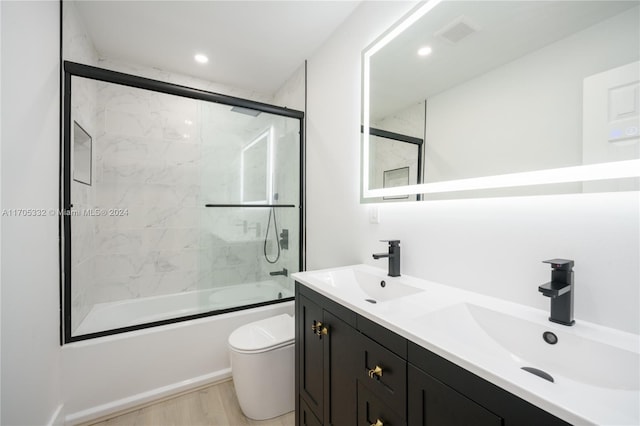 full bathroom with vanity, toilet, wood-type flooring, and bath / shower combo with glass door