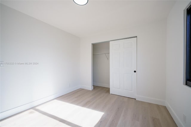 unfurnished bedroom featuring light hardwood / wood-style flooring and a closet