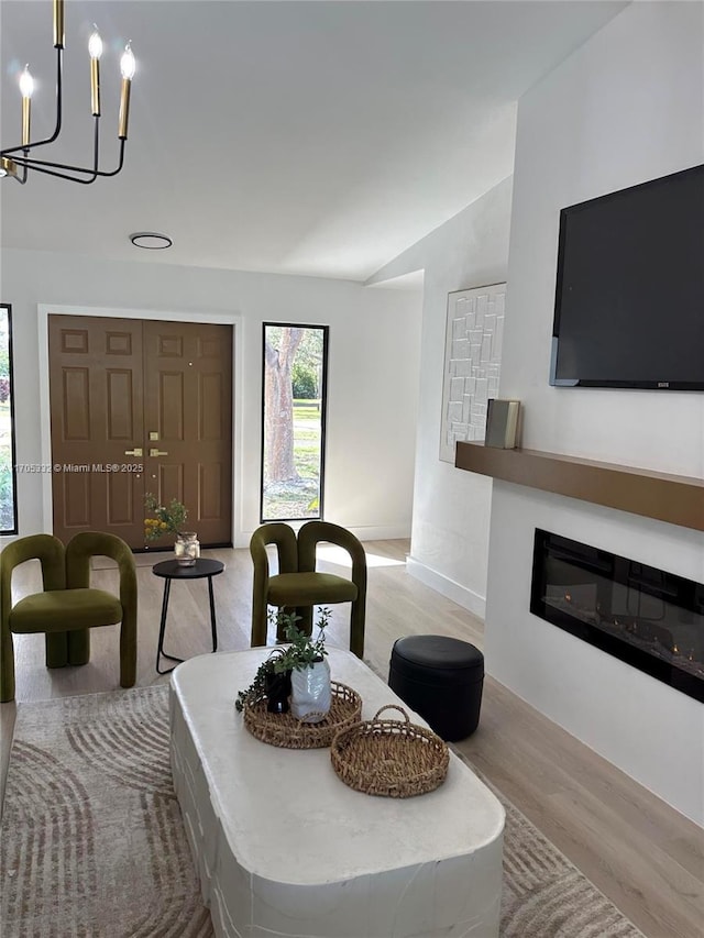 dining area with lofted ceiling, an inviting chandelier, and light hardwood / wood-style floors