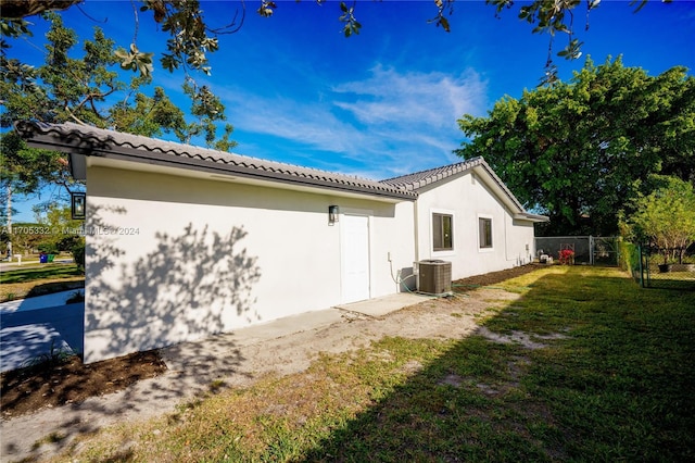 view of property exterior with central AC and a yard